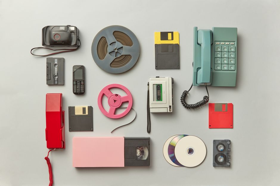 Collection of vintage gadgets including telephones, cassettes, and floppy disks.